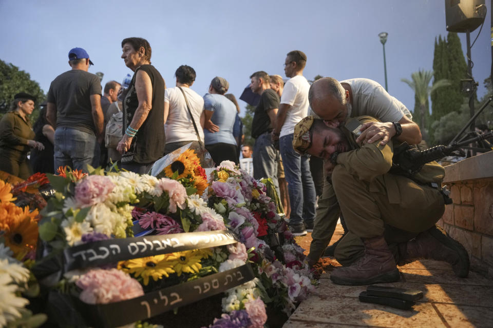 Friends and relatives of Ilai Bar Sade mourn next to his grave during his funeral at the military cemetery in Tel Aviv, Israel, Monday, Oct. 9, 2023. Bar Sade was killed after Hamas militants stormed from the blockaded Gaza Strip into nearby Israeli towns. Israel's vaunted military and intelligence apparatus was caught completely off guard, bringing heavy battles to its streets for the first time in decades. (AP Photo/Erik Marmor)
