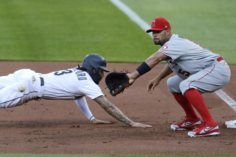 Seattle Mariners' J.P. Crawford, left, dives back safely to first base as Los Angeles Angels first baseman Albert Pujols waits for the ball on a pick-off attempt in the third inning of a baseball game Wednesday, Aug. 5, 2020, in Seattle. (AP Photo/Elaine Thompson)