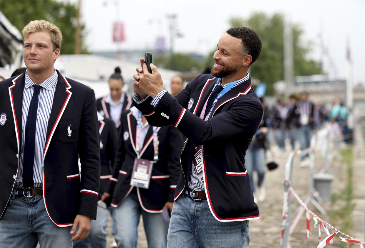 Stephen Curry of the United States takes a photo prior to the opening ceremony. / Credit: Quinn Rooney / AP