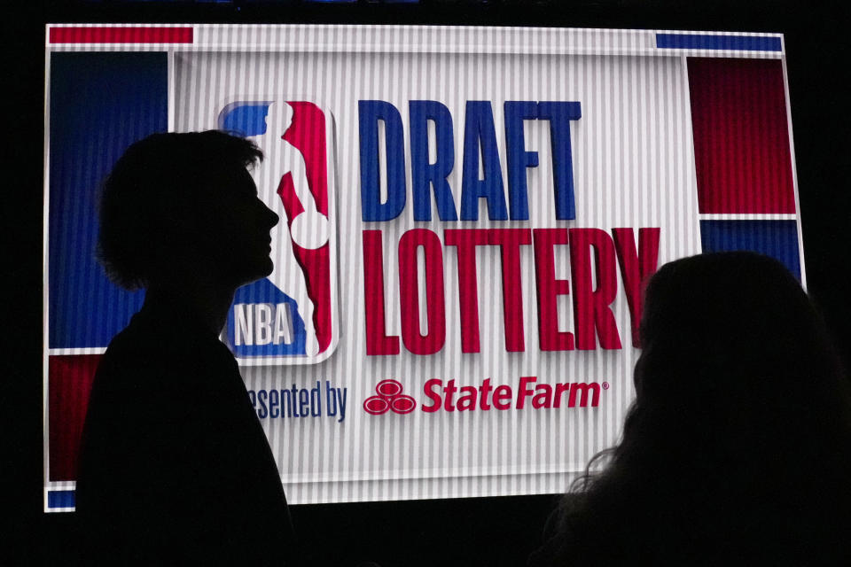 NBA basketball draft prospect Johnny Furphy, left, looks at the draft lottery order in front of a draft lottery sign before the draft lottery in Chicago, Sunday, May 12, 2024. (AP Photo/Nam Y. Huh)