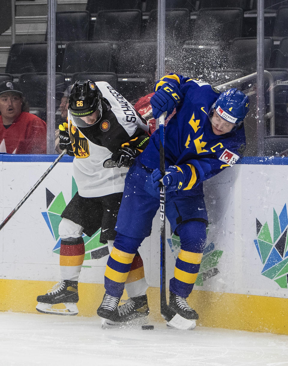 Sweden's Emil Andrae (4) is checked by Germany's Markus Schweiger (26) during the second period of an IIHF world junior hockey championships game Monday, Aug. 15, 2022, in Edmonton, Alberta. (Jason Franson/The Canadian Press via AP)