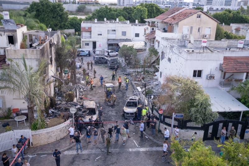 First responders, Israeli security forces and people gather among rubble and damaged vehicles in Kiryat Bialik, following a reported attack by the pro-Iranian Hezbollah movement. Ilia Yefimovich/dpa