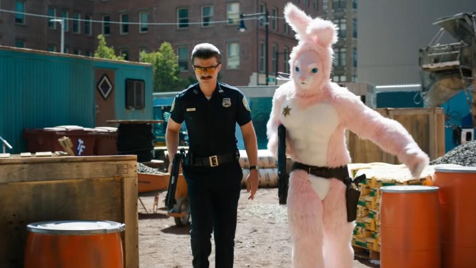 A police officer and a man dressed as a pink rabbit