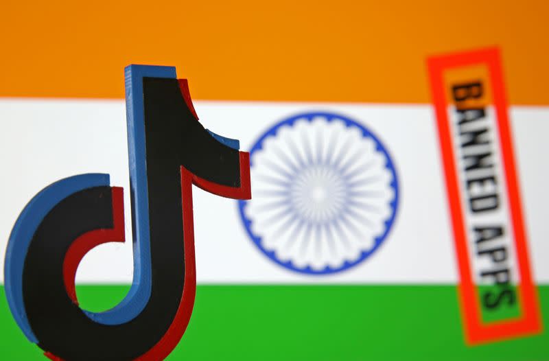 A 3d printed Tik Tok logo is seen in front of a displayed Indian flag and a "Banned app" sign