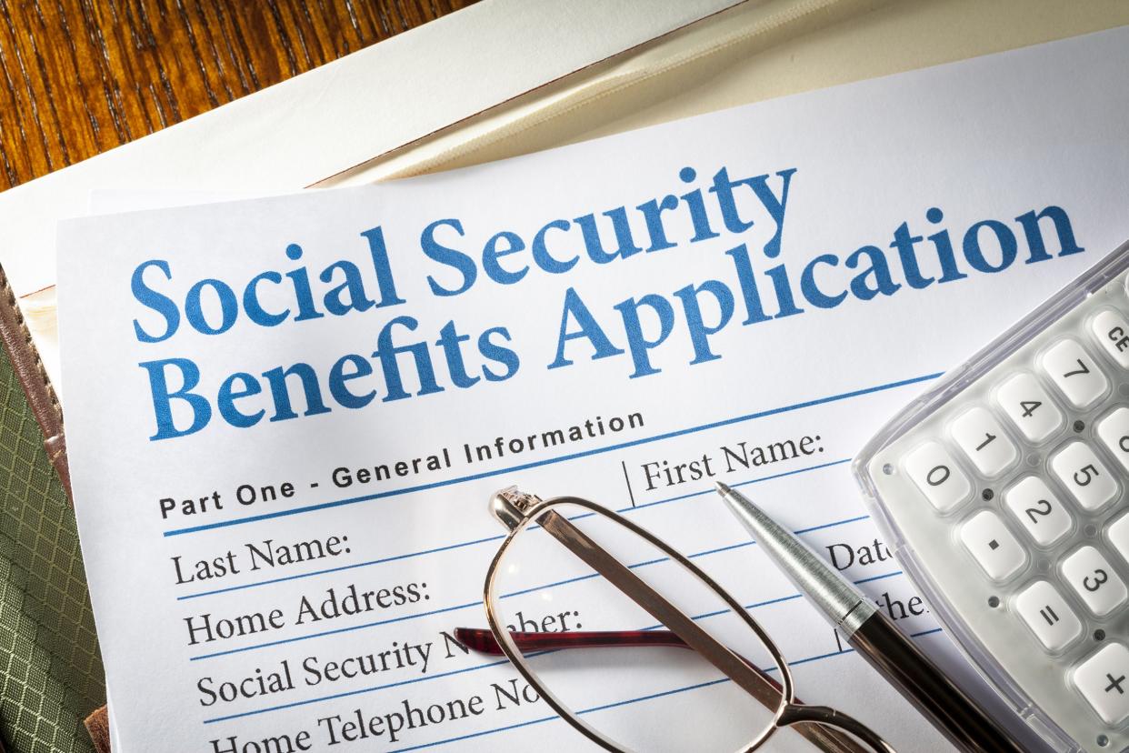 Social Security benefits application form with glasses, pen, and calculator