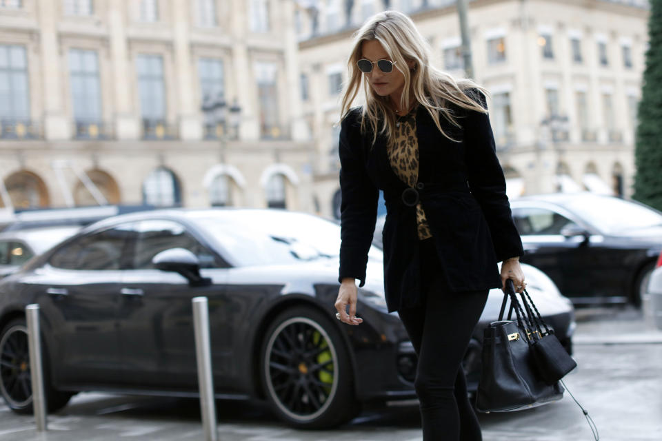 Kate Moss walks past a luxury car as she arrives at Paris Fashion Week earlier this year. Photo: Getty