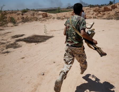 A fighter of Libyan forces allied with the U.N.-backed government runs for cover during a battle with Islamic States fighters in Sirte. REUTERS/Goran Tomasevic