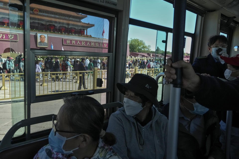 Commuters with face masks on a bus watch crowds of visitors touring Tiananmen Gate during the May Day holiday period in Beijing, Sunday, April 30, 2023. (AP Photo/Andy Wong)