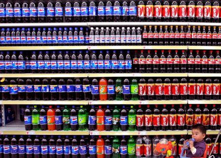 A boy sitting in a toy tricycle is pushed past shelves of bottled beverages at a supermarket in Nanjing, east China's Jiangsu province in this April 10, 2006 file photo. REUTERS/Stringer/Files