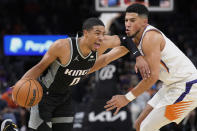 Sacramento Kings guard Tyrese Haliburton (0) drives on Phoenix Suns guard Devin Booker during the first half of an NBA basketball game, Wednesday, Oct. 27, 2021, in Phoenix. (AP Photo/Rick Scuteri)