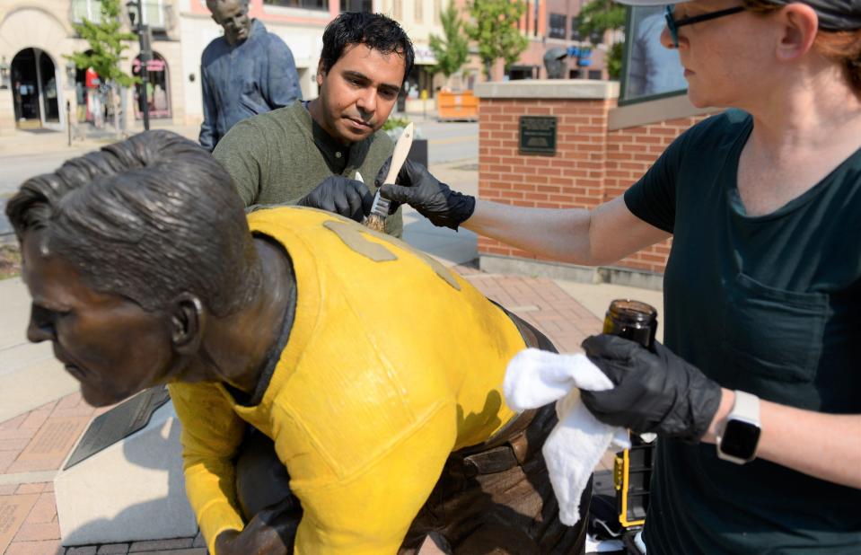 Oscar León and Jessica LoPresti of Sculpture Resource in Highland Park, Illinois, add a brown wash to the Johnny Blood statue in Packers Heritage Plaza in downtown Green Bay on Sept. 14, 2022.