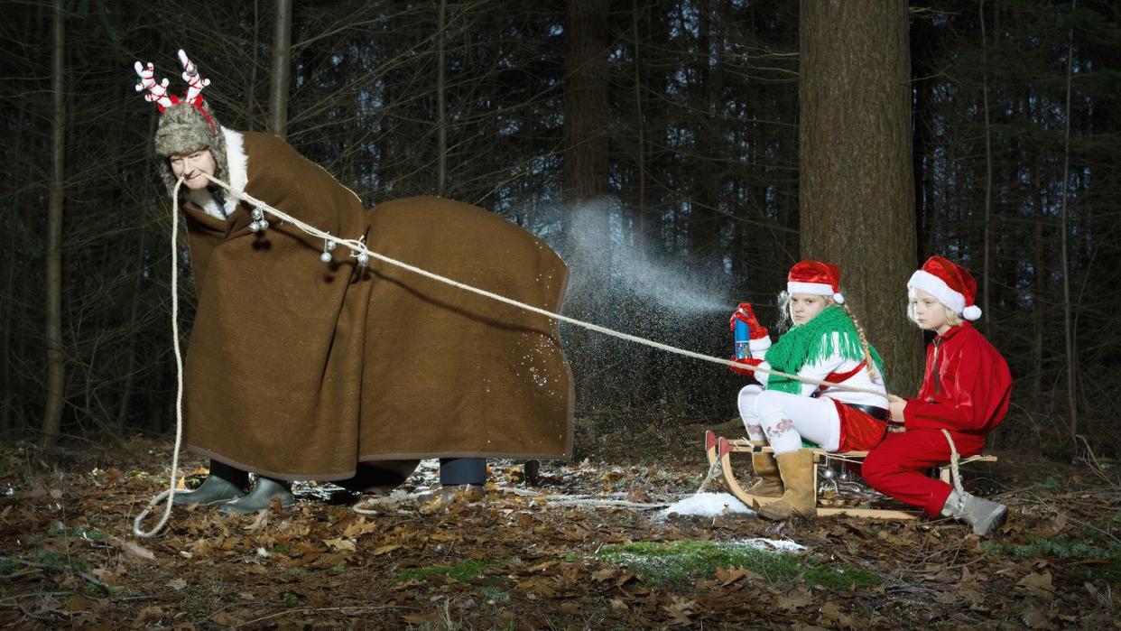 father disguised as reindeer pulling sleigh with children in santa costume