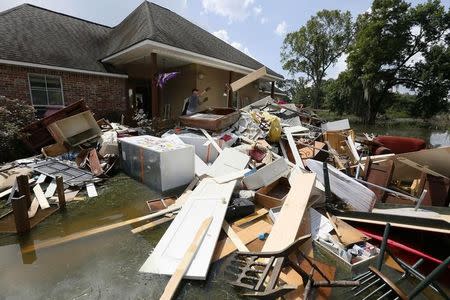 A man throws flood damaged material into a pile of debris in St. Amant, Louisiana, U.S., August 21, 2016. REUTERS/Jonathan Bachman