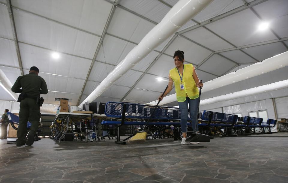A worker sweeps the floor as the U.S. Border Patrol unveiled a new 500-person tent facility during a media tour Friday, June 28, 2019, in Yuma, Ariz. The facility will be used to process detained immigrant children and families who cross the U.S. border. The Border Patrol says it will start placing families there on Friday night. (AP Photo/Ross D. Franklin)