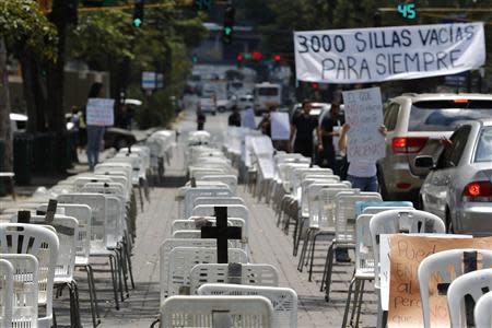 Anti-government protesters placed black crosses on white chairs, representing victims who died from violence, during a demonstration in Caracas March 15, 2014. REUTERS/Tomas Bravo