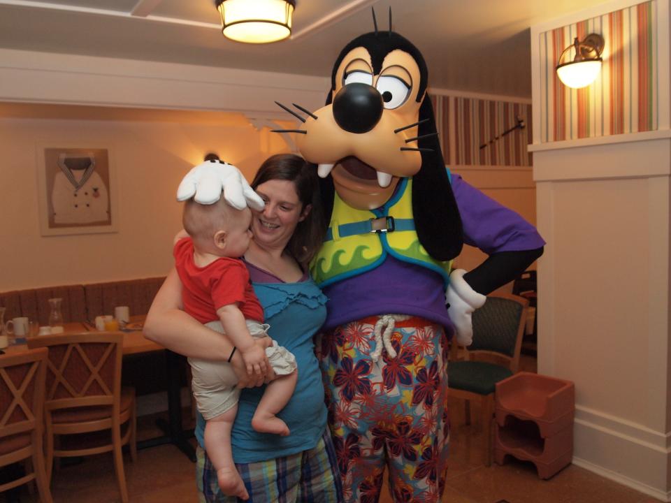 kari holding her son as they meet goofy at disney world