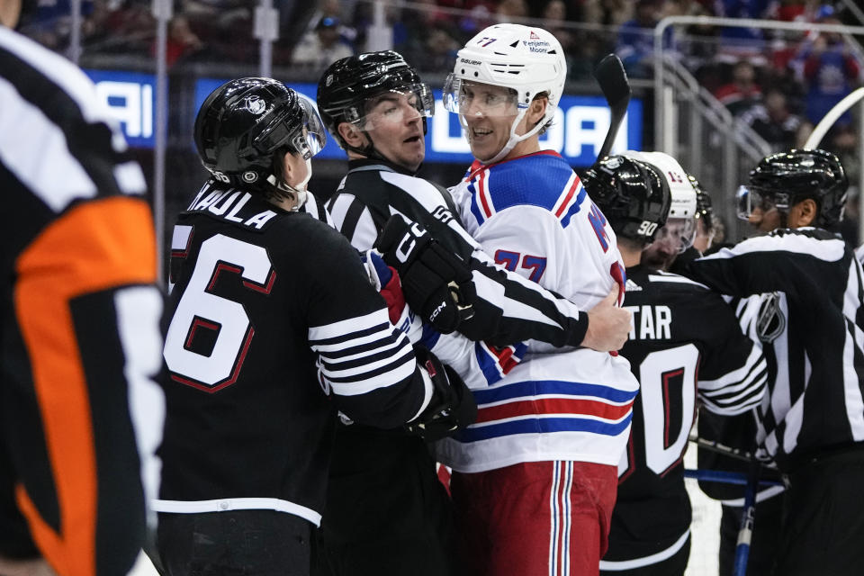 A referee separates New Jersey Devils' Erik Haula (56) and New York Rangers' Niko Mikkola (77) during the second period of an NHL hockey game Thursday, March 30, 2023, in Newark, N.J. (AP Photo/Frank Franklin II)