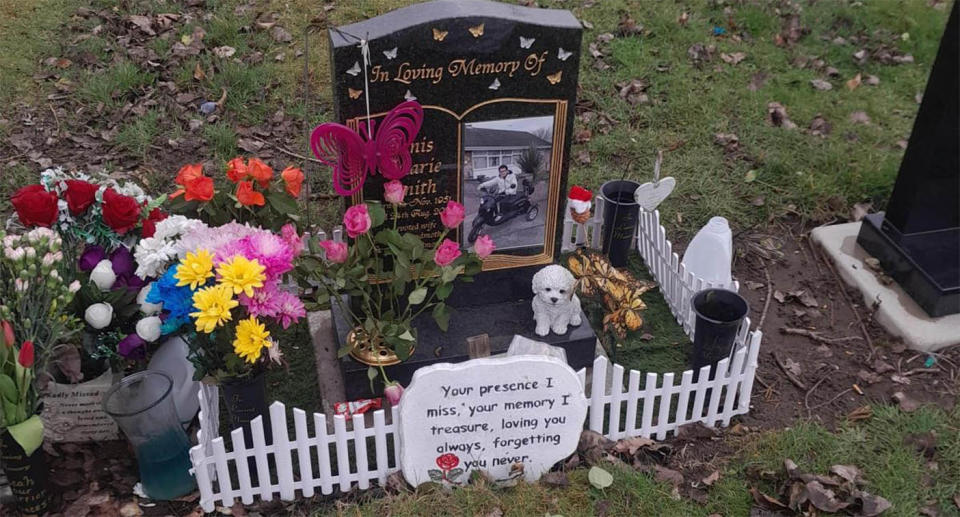 A gravestone is decorated with flowers and a small white fence, which council is ordering to be removed.