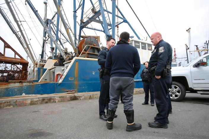 La policía de New Bedford habla con un pescador durante una investigación de un incidente con armas de fuego a bordo de un barco de pesca.