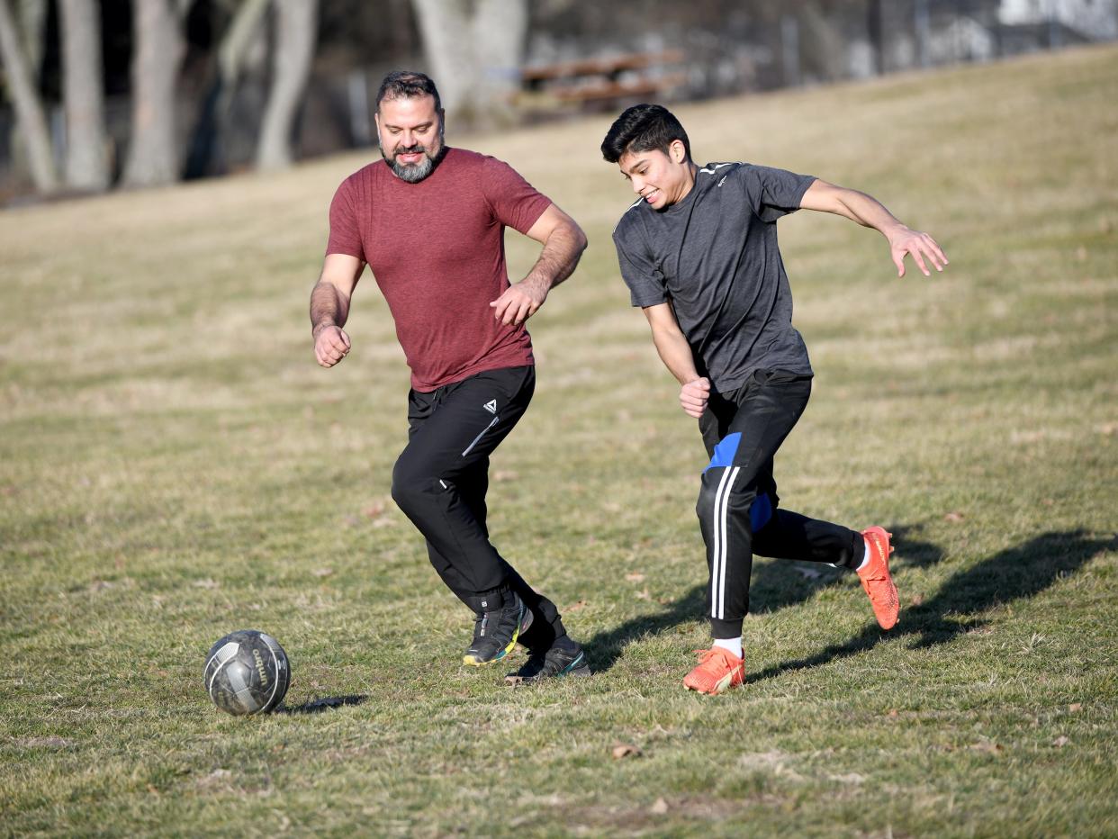 Raul Sagovia of Jackson Township chases a soccer ball with son Luis Sagovia as they take advantage on an unseasonably warm winter day at North Park in Jackson Township.