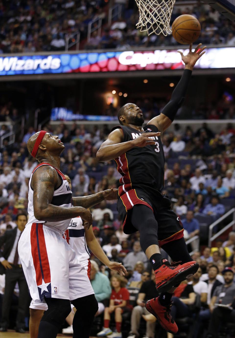 Miami Heat guard Dwyane Wade (3) shoots in front of Washington Wizards forward Al Harrington (7) in the first half of an NBA basketball game, Monday, April 14, 2014, in Washington. (AP Photo/Alex Brandon)