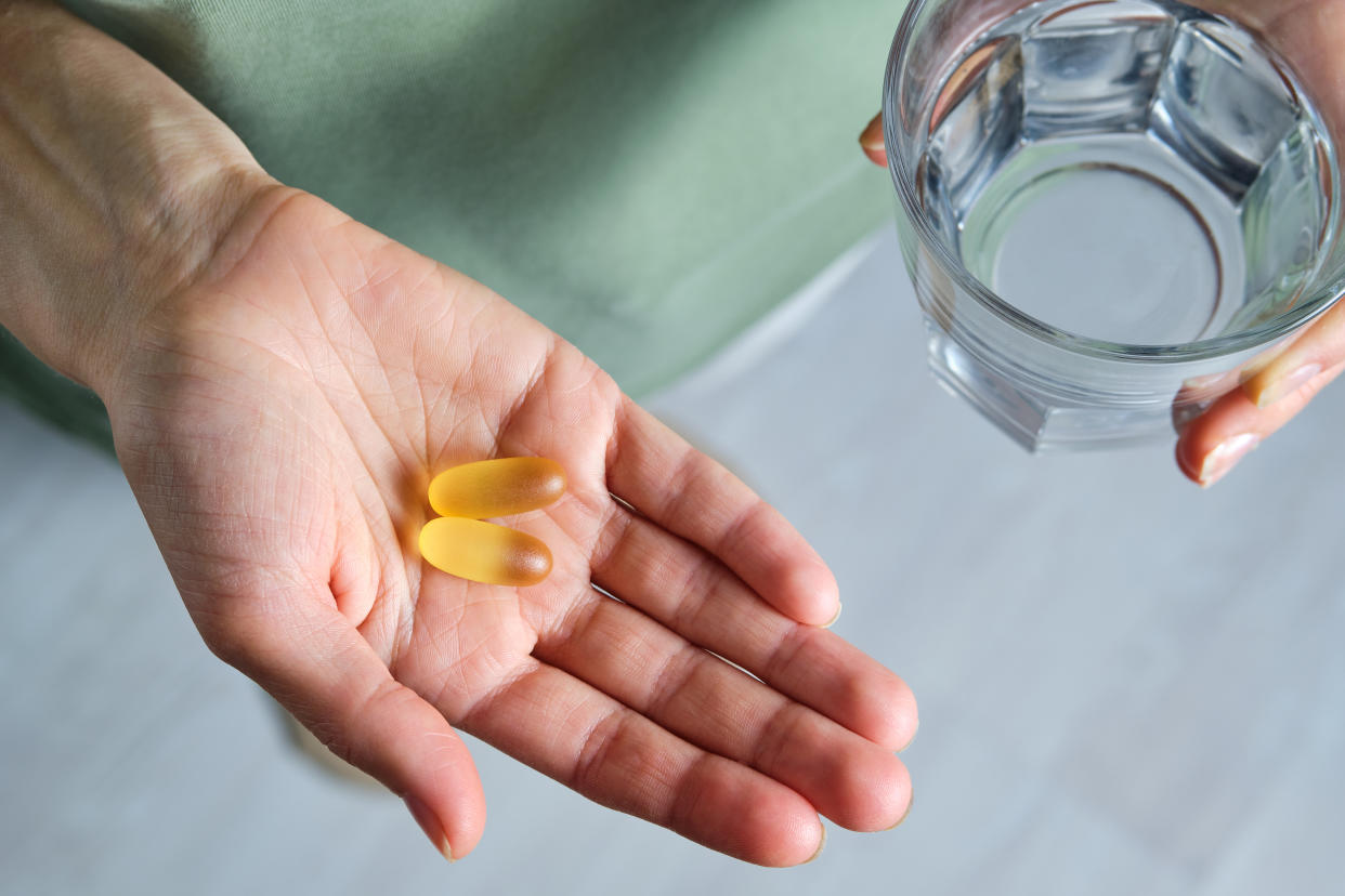 The woman is Holding omega-3 fish oil capsules or medications, and a glass of water. Healthy lifestyle, prevention and treatment of diseases. The girl Takes and Drinks food supplements and vitamins. Biologically active additive. Intake of healthy fats.