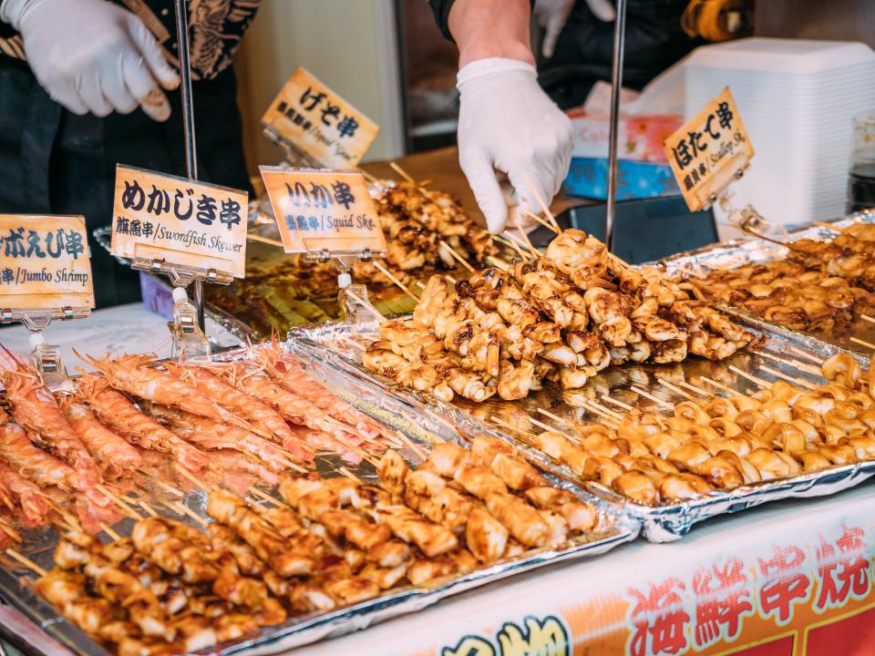 Seafood skewers including shrimp, swordfish, and squid laid out on silver trays.