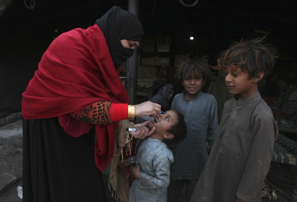 A health worker administers a polio vaccine to a child in a slum area of Peshawar, Pakistan, Monday, Jan. 24, 2022. Pakistani authorities launched the year's first anti-polio campaign even as coronavirus cases suddenly rise in an effort to eradicate the crippling children's disease. (AP Photo/Muhammad Sajjad)