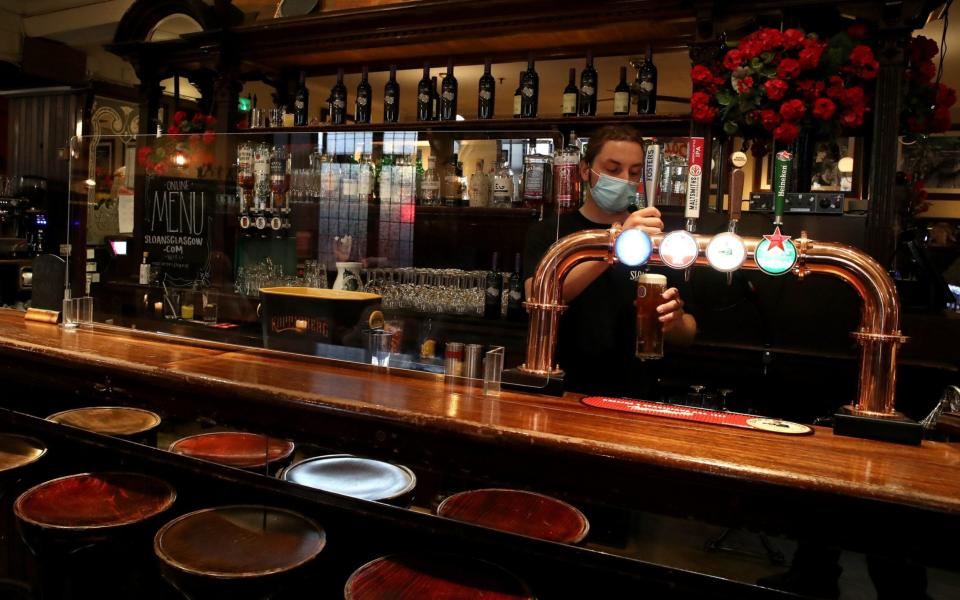 Barman George Alston in Sloans in Glasgow pours a pint  - PA