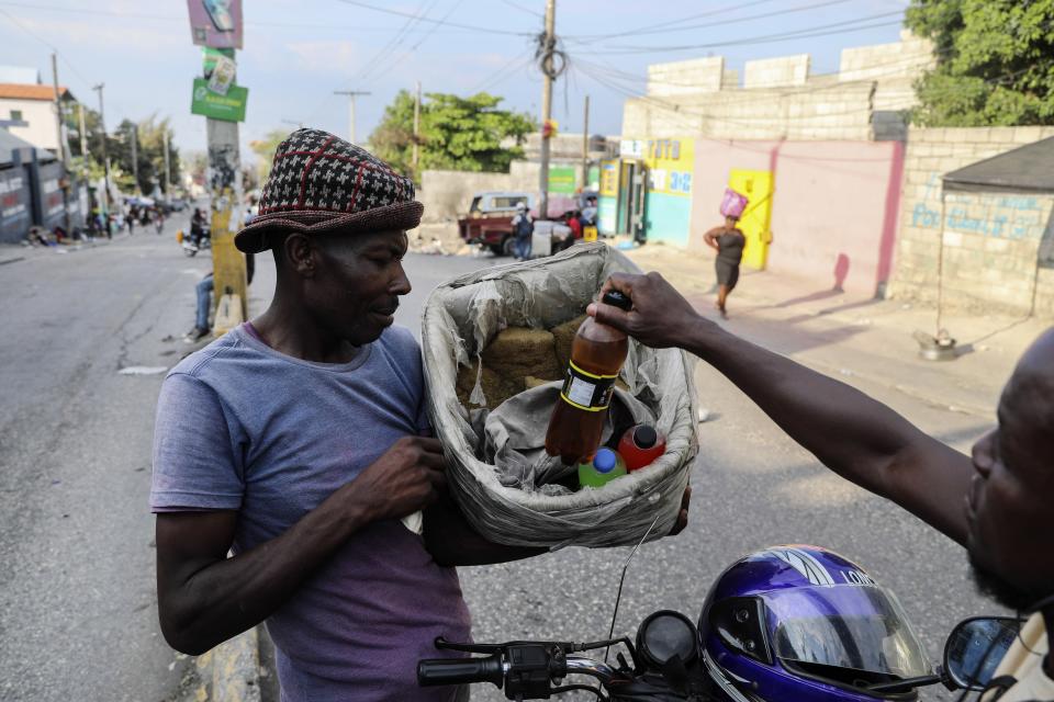 A customer purchases a beverage from a street vendor in Port-au-Prince, Haiti, Wednesday, April 10, 2024. (AP Photo/Odelyn Joseph)