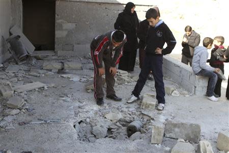 Civilians inspect a site hit by rockets fired from Syria at the Lebanese border town of Arsal January 17, 2014. REUTERS/Ahmad Shalha