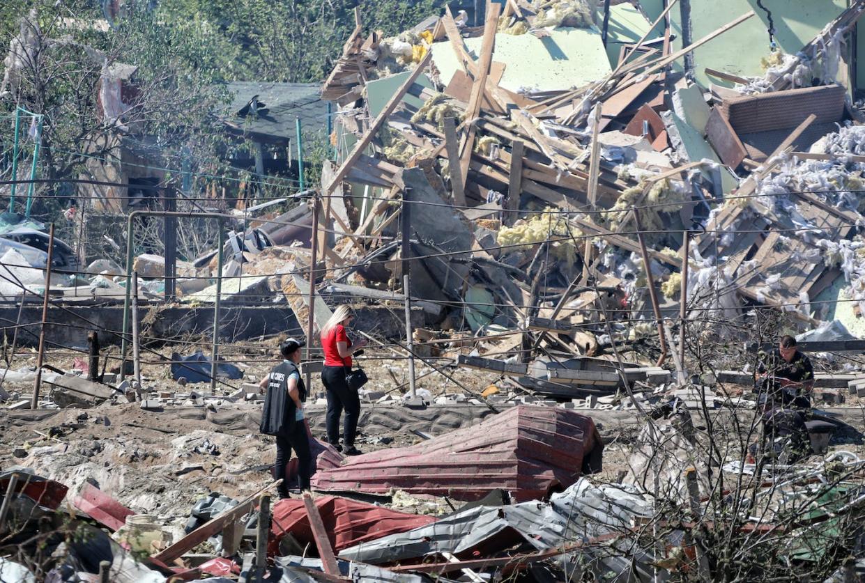 A Ukrainian war crimes investigator photographs the aftermath of a Russian missile attack in Zatoka, Ukraine, on July 26, 2022. <a href="https://media.gettyimages.com/photos/war-crimes-prosecutor-and-a-woman-stand-among-the-rubble-after-a-picture-id1242137286?s=2048x2048" rel="nofollow noopener" target="_blank" data-ylk="slk:Nina Liashonok/Ukrinform/Future Publishing via Getty Images;elm:context_link;itc:0;sec:content-canvas" class="link ">Nina Liashonok/Ukrinform/Future Publishing via Getty Images </a>