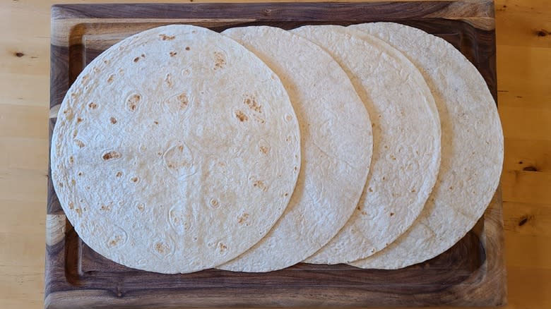 four flour tortillas on a cutting board