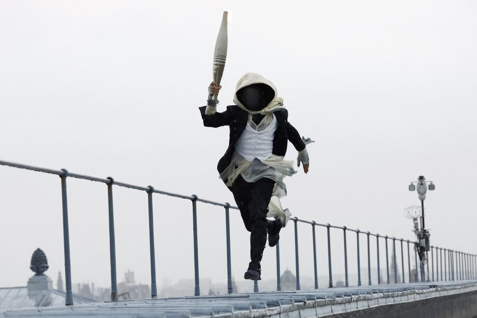 A torch bearer runs atop the Musee d'Orsay, in Paris, France, during the opening ceremony of the 2024 Summer Olympics, Friday, July 26, 2024. (Peter Cziborra/Pool Photo via AP)