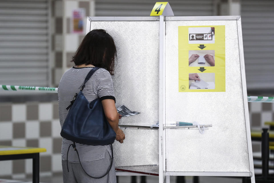 A voter casts her ballot at the Chung Cheng High School polling center in Singapore, Friday, July 10, 2020. Wearing masks and plastic gloves, Singaporeans began voting in a general election that is expected to return Prime Minister Lee Hsien Loong's long-governing party to power. (AP Photo)