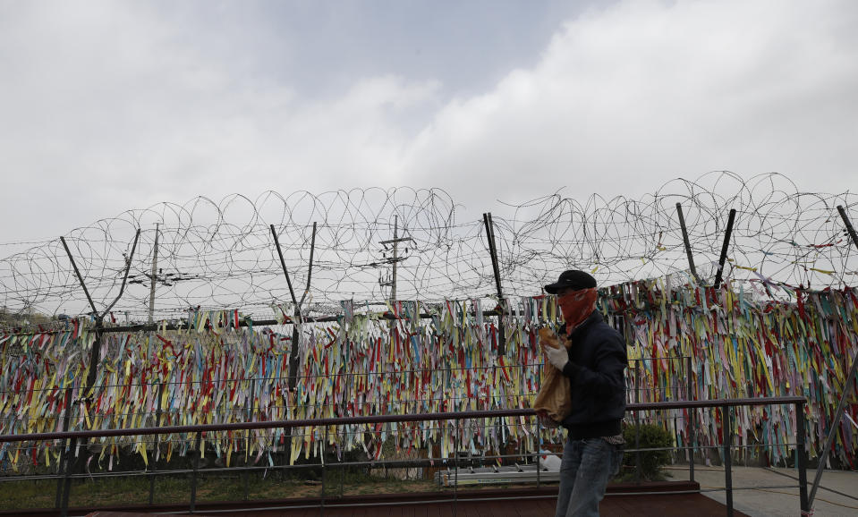 A worker carries repair material near a wire fence decorated with ribbons written with messages wishing for the reunification of the two Koreas at the Imjingak Pavilion in Paju, South Korea, Wednesday, April 22, 2020. South Korean officials reported no unusual activity in North Korea on Tuesday following unconfirmed media reports that leader Kim Jong Un was in fragile health after surgery. (AP Photo/Lee Jin-man)