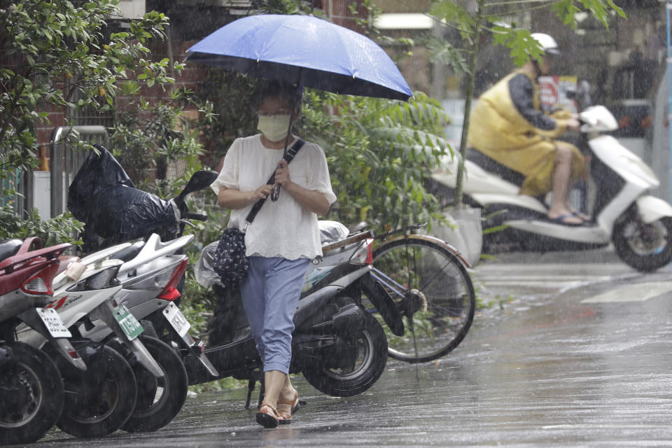 A woman walks in heavy rain after Typhoon Saola moves away in Taipei, Taiwan, Thursday, Aug. 31, 2023. (AP Photo/Chiang Ying-ying)