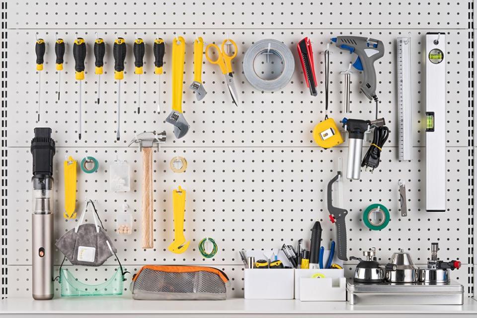 various hand tools hanging on white colored pegboard with blank space front view