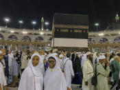 Muslim women pilgrims pose for photographs for their relative near the Kaaba, the cubic building at the Grand Mosque, in the Muslim holy city of Mecca, Saudi Arabia, early Friday, Aug. 17, 2018. The annual Islamic pilgrimage draws millions of visitors each year, making it the largest yearly gathering of people in the world. (AP Photo/Dar Yasin)