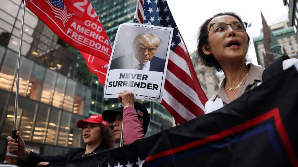 Supporters hold placards and flags following the announcement of the verdict in Trump's criminal trial. - Andrew Kelly/Reuters