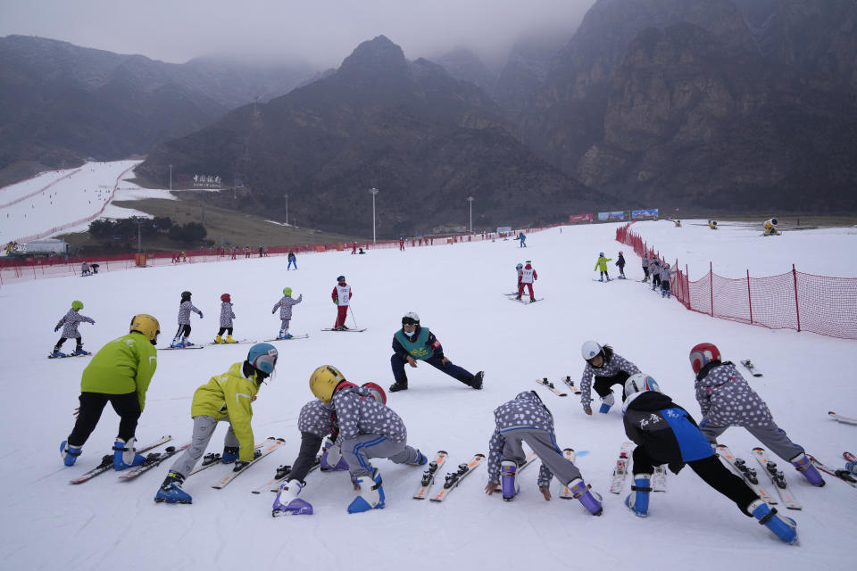 School children warm up before ski lessons at the Vanke Shijinglong Ski Resort in Yanqing on the outskirts of Beijing, China, Thursday, Dec. 23, 2021. The Beijing Winter Olympics is tapping into and encouraging growing interest among Chinese in skiing, skating, hockey and other previously unfamiliar winter sports. It's also creating new business opportunities. (AP Photo/Ng Han Guan)