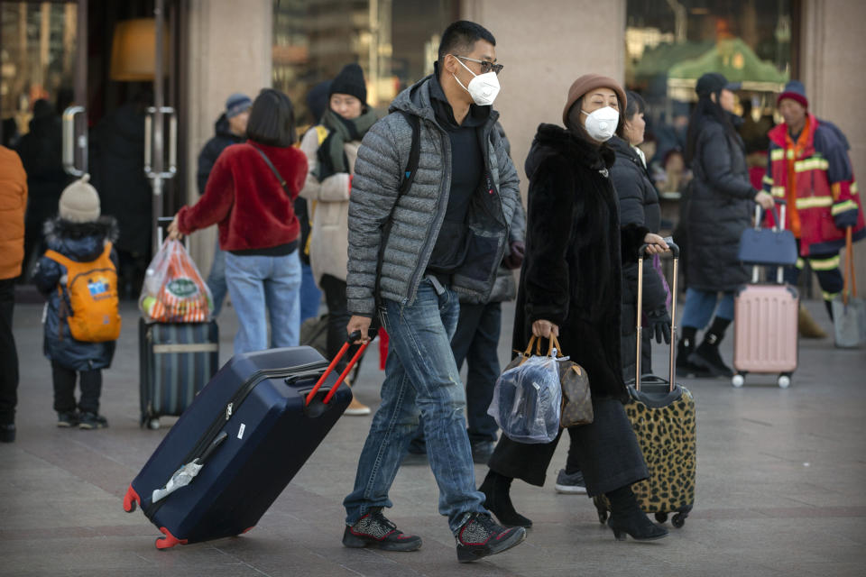 Travelers wear face masks as they walk outside of the Beijing Railway Station in Beijing, Monday, Jan. 20, 2020. China reported Monday a sharp rise in the number of people infected with a new coronavirus, including the first cases in the capital. The outbreak coincides with the country's busiest travel period, as millions board trains and planes for the Lunar New Year holidays. (AP Photo/Mark Schiefelbein)