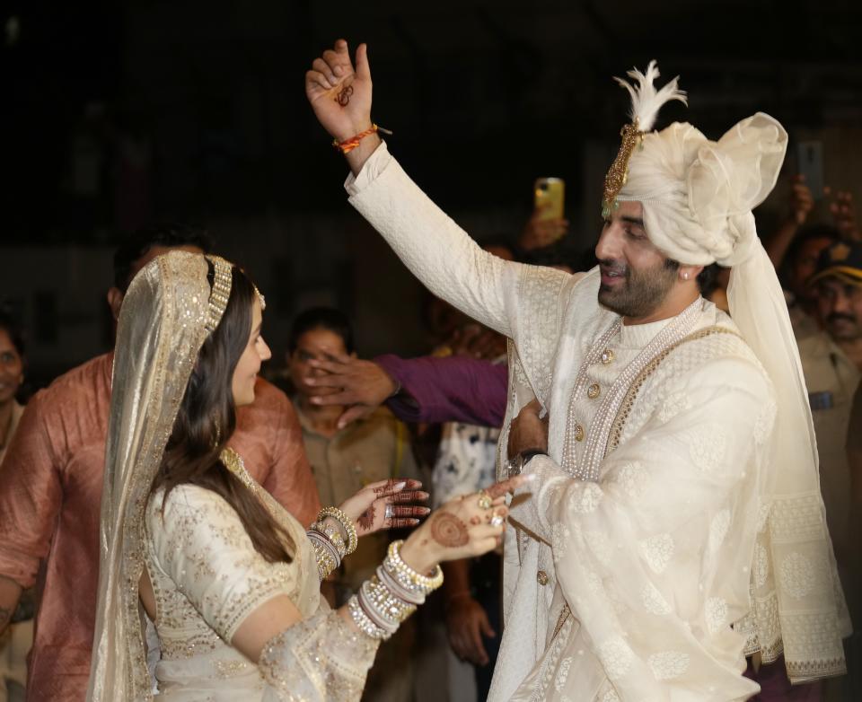 Bollywood actors Ranbir Kapoor, right and Alia Bhatt pose for photographs after their wedding outside their residence in Mumbai, India, Thursday, April 14, 2022. (AP Photo/Rajanish Kakade)