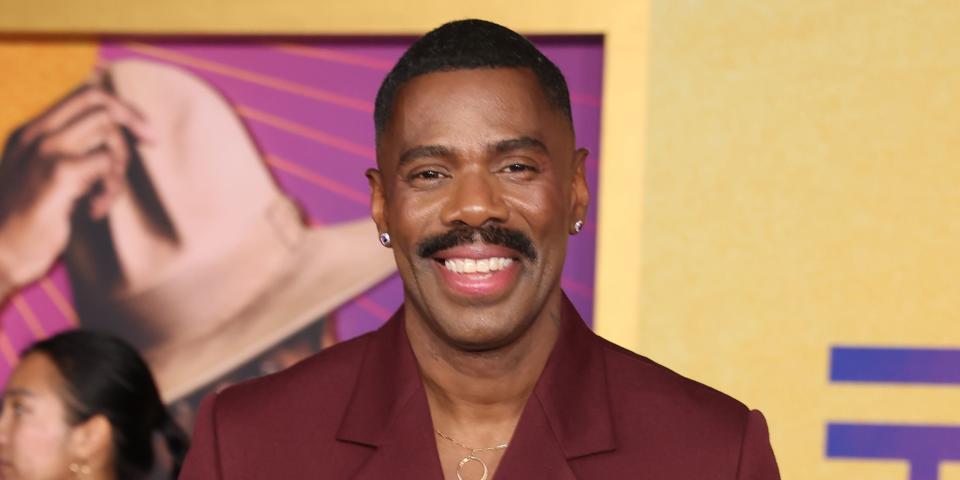 colman domingo smiles in a maroon suit with gold broach and jewellery