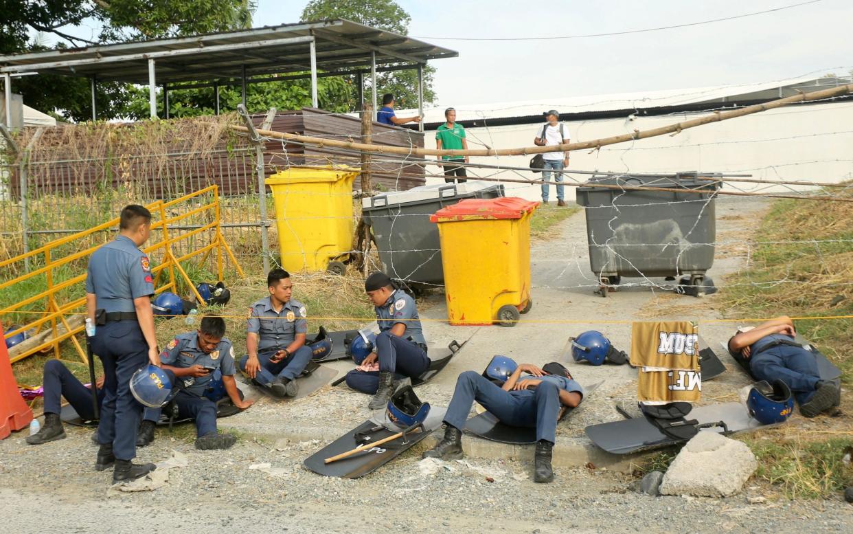 Anti-riot police rest outside the Kingdom of Jesus Christ compound in Davao city