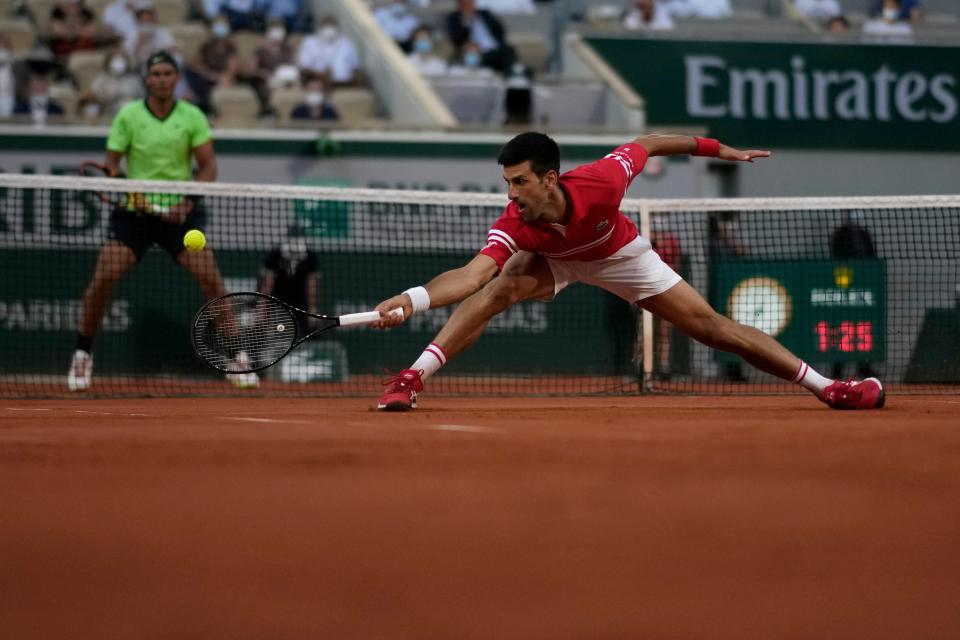 Novak Djokovic stretches for a backhand with Rafael Nadal watching (AP)