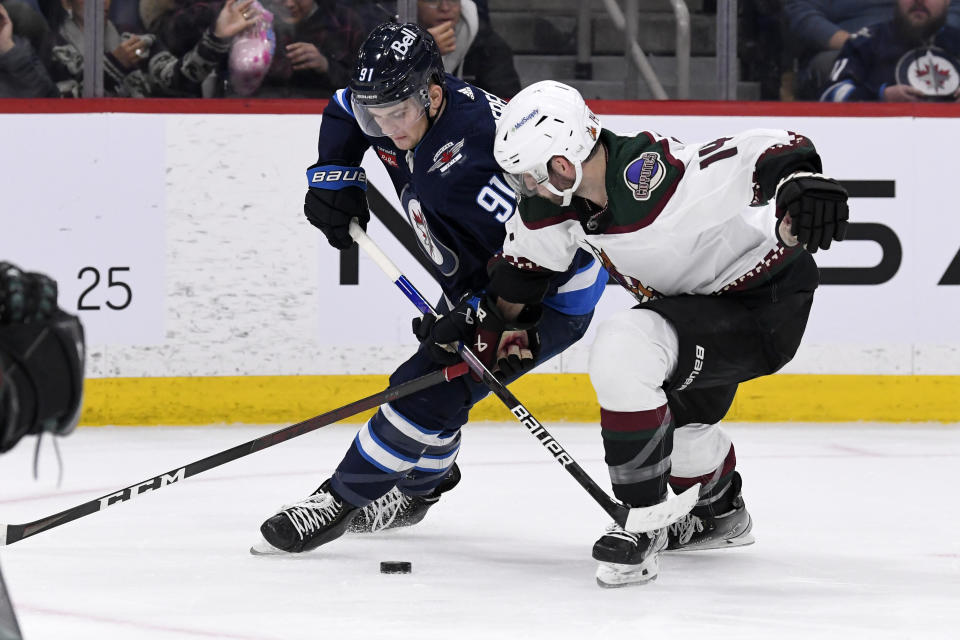 Arizona Coyotes defenseman Shayne Gostisbehere (14) and Winnipeg Jets center Cole Perfetti (91) battle for the puck during second-period NHL hockey game action in Winnipeg, Manitoba, Sunday, Jan. 15, 2023. (Fred Greenslade/The Canadian Press via AP)