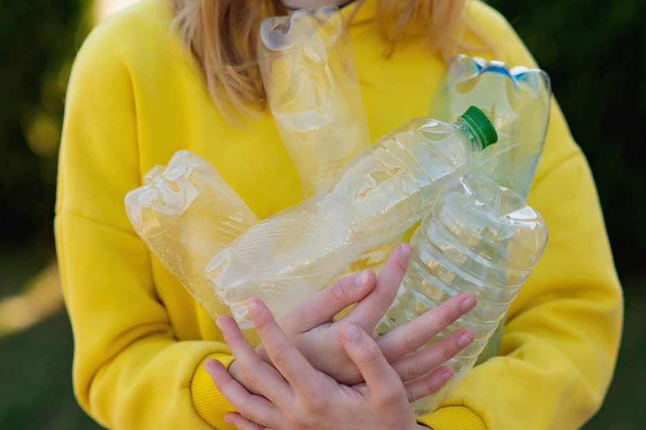 Woman holding several empty water bottles
