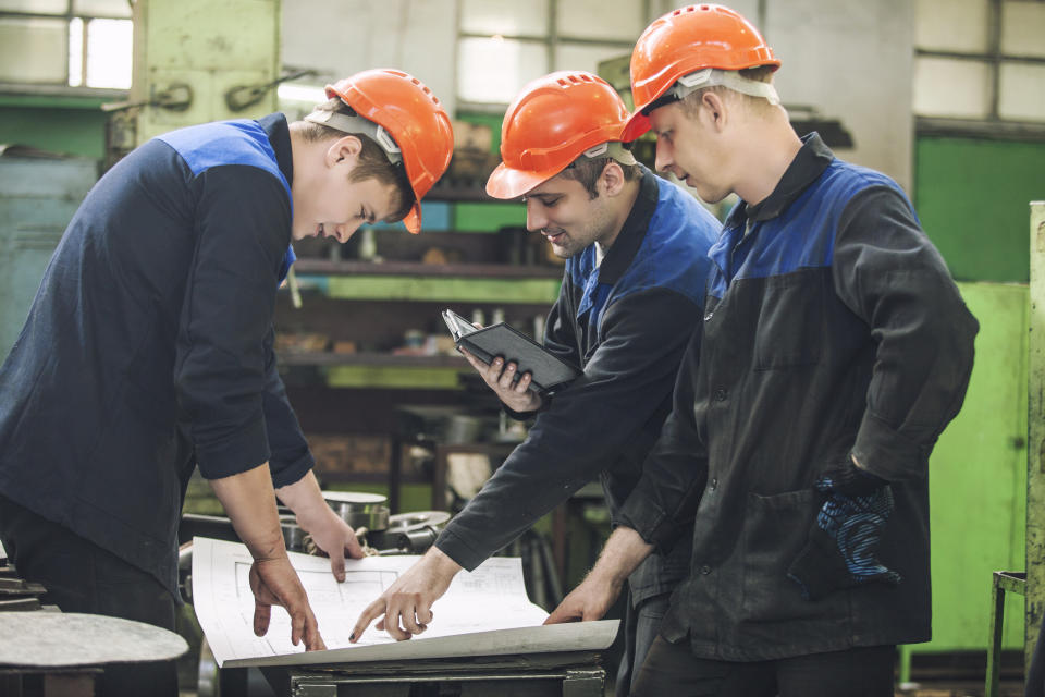 Three men looking over blueprints in an energy facility