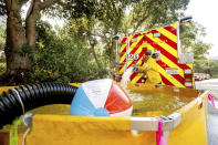 Los Angeles County firefighter Brad Auman fills a water tank while helping battle the Lake Fire in the Angeles National Forest north of Santa Clarita, Calif., on Thursday, Aug. 13, 2020. The beach ball is used to prevent air from entering intake hoses while refilling fire engine water tanks. (AP Photo/Noah Berger)